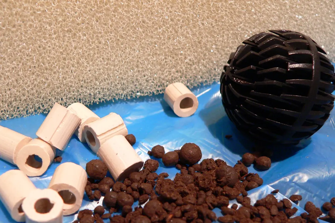 Filter media laid out together: hollow ceramic tubes, a perforated plastic bio-ball, brown clay granules and a block of foam sponge